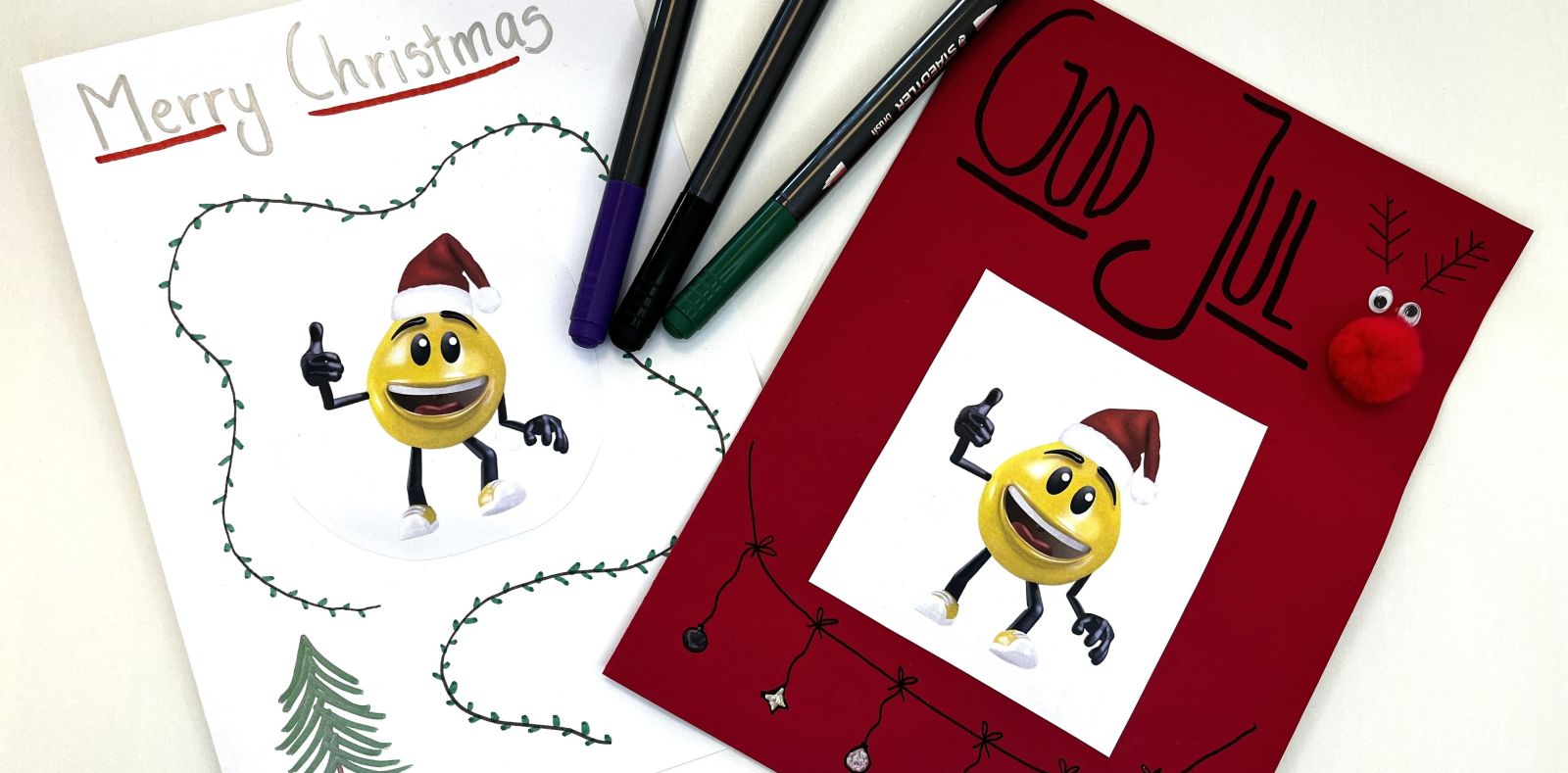 Två julkort med tecknade figurer och texten Merry Christmas och God Jul omgivna av färgpennor